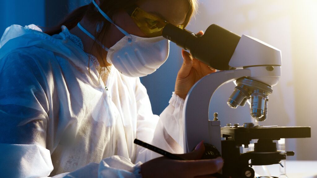 Photographie d'une femme qui regarde dans un microscope